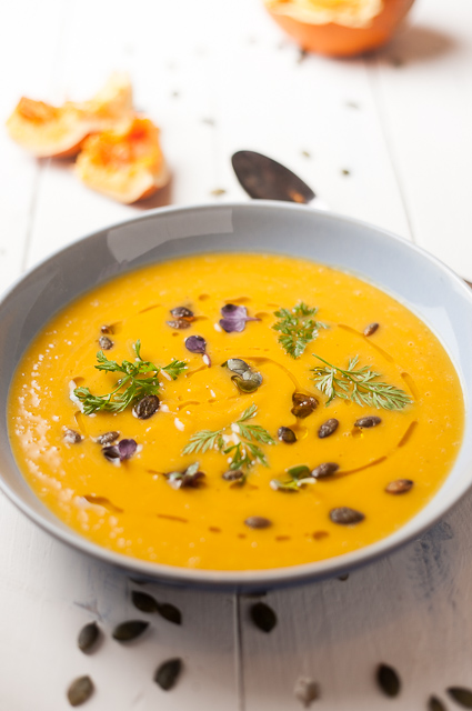 Beautiful bowl of pumpkin soup with a drizzle of oil, pumpkin seeds and micro herbs