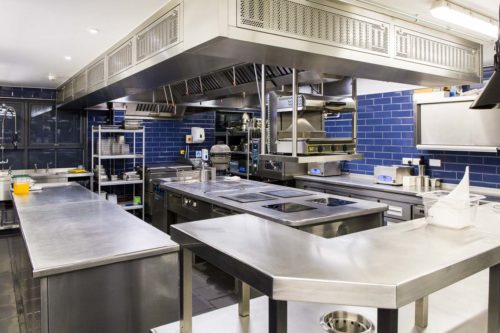 Spotlessly clean commercial kitchen with stainless steel work surfaces and blue subway tile at The Oxford Blue Pub