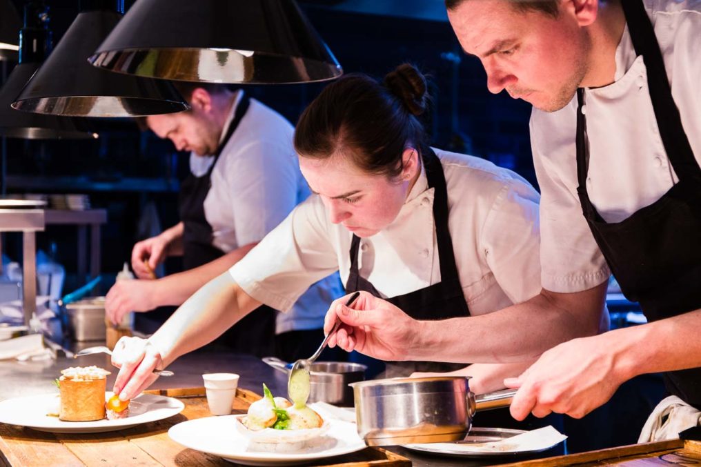 Three chefs looking very focused, plating up food on the pass of The Oxford Blue Pub, with Ami Blakey and Steven Ellis